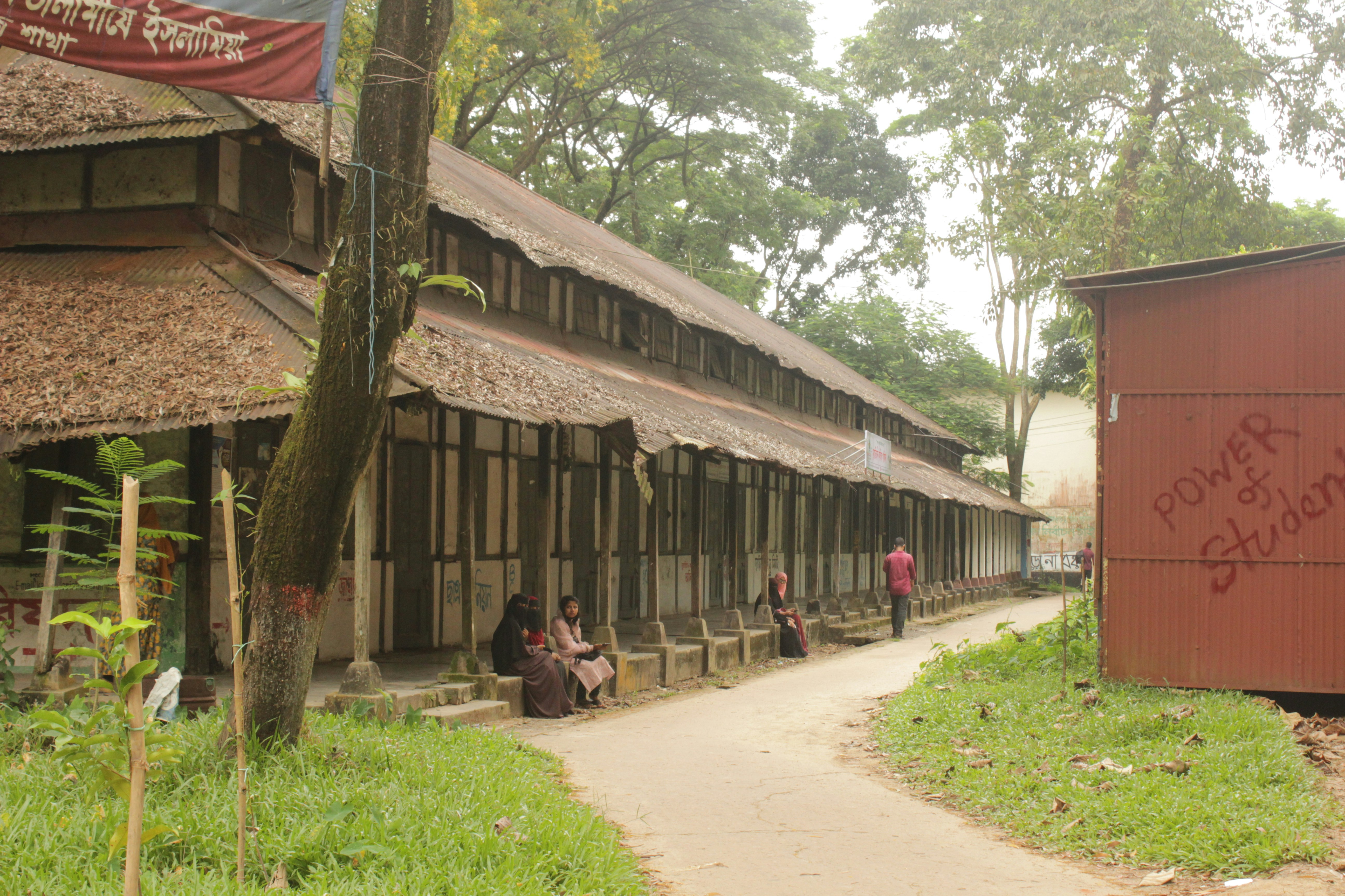 A traditional school building in rural Bangladesh with students and teachers outside